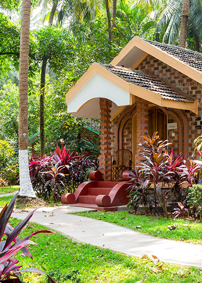 Entrance of the Royal Villa surrounded by lush green palm trees | Kairali-The Ayurvedic Healing Village