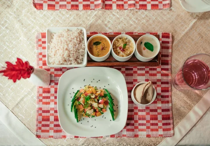 Overhead view of a sattvic vegetarian thali with rice, curries, and salad at Kairali